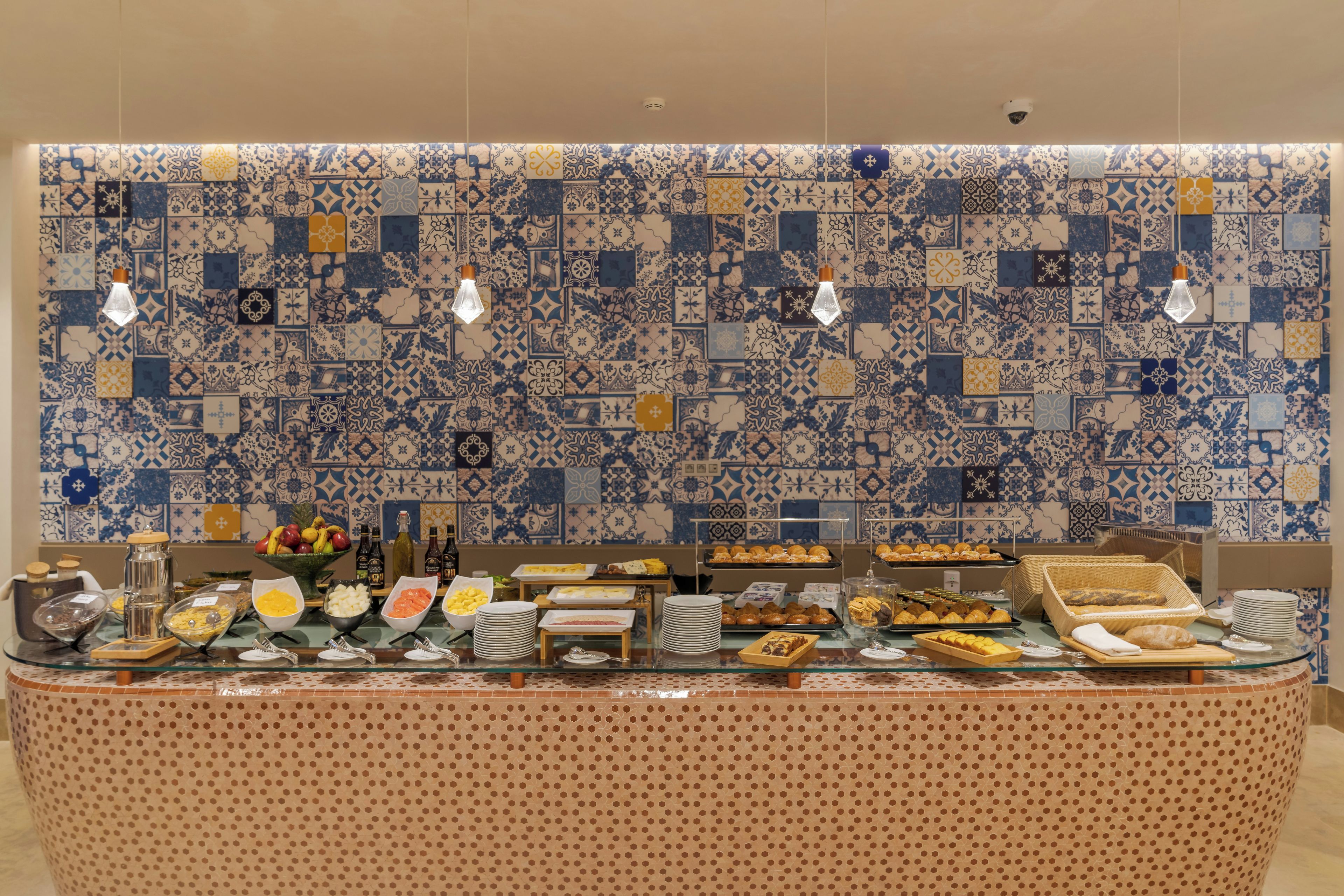 A buffet setup with a variety of food items and a patterned tile backsplash.