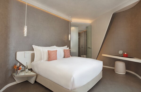 Une chambre d’hôtel moderne avec un grand lit, des tables de chevet, un miroir et un espace douche.