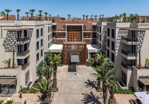 A modern building with multiple balconies and a central courtyard with palm trees. - Pestana Cr7 Marrakech (Marrakech)