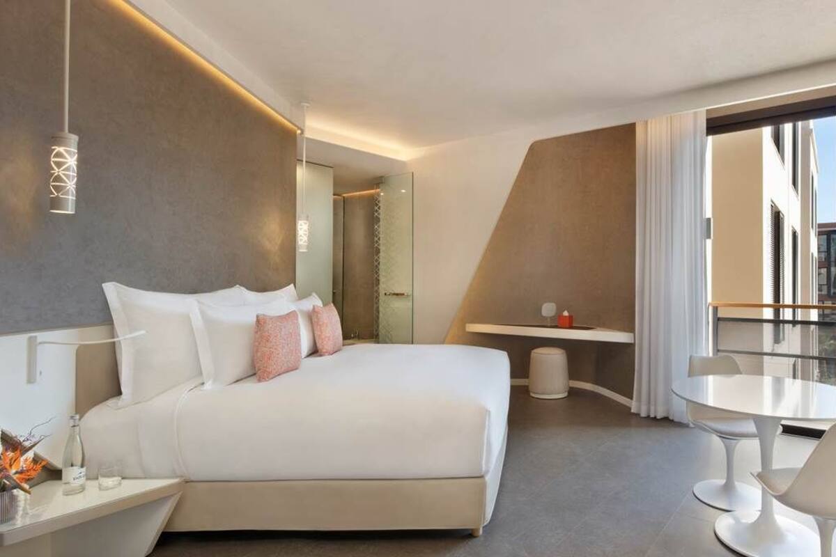Een moderne hotelkamer met een groot bed, een balkon met televisie en een zithoek.