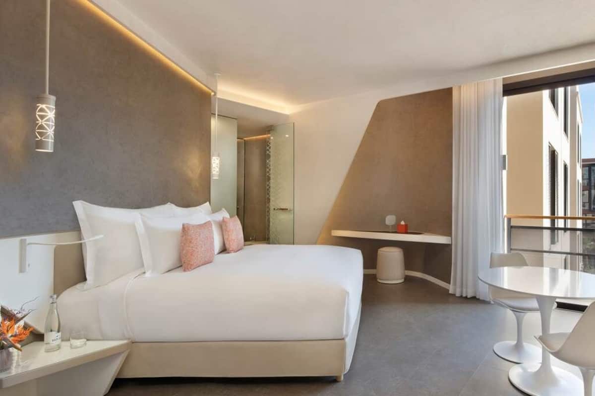 Ett modernt hotellrum med en stor säng, en balkong med tv och en matplats.