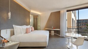 A modern hotel room with a large bed, a balcony with a TV, and a dining area. - Pestana Cr7 Marrakech (Marrakech)