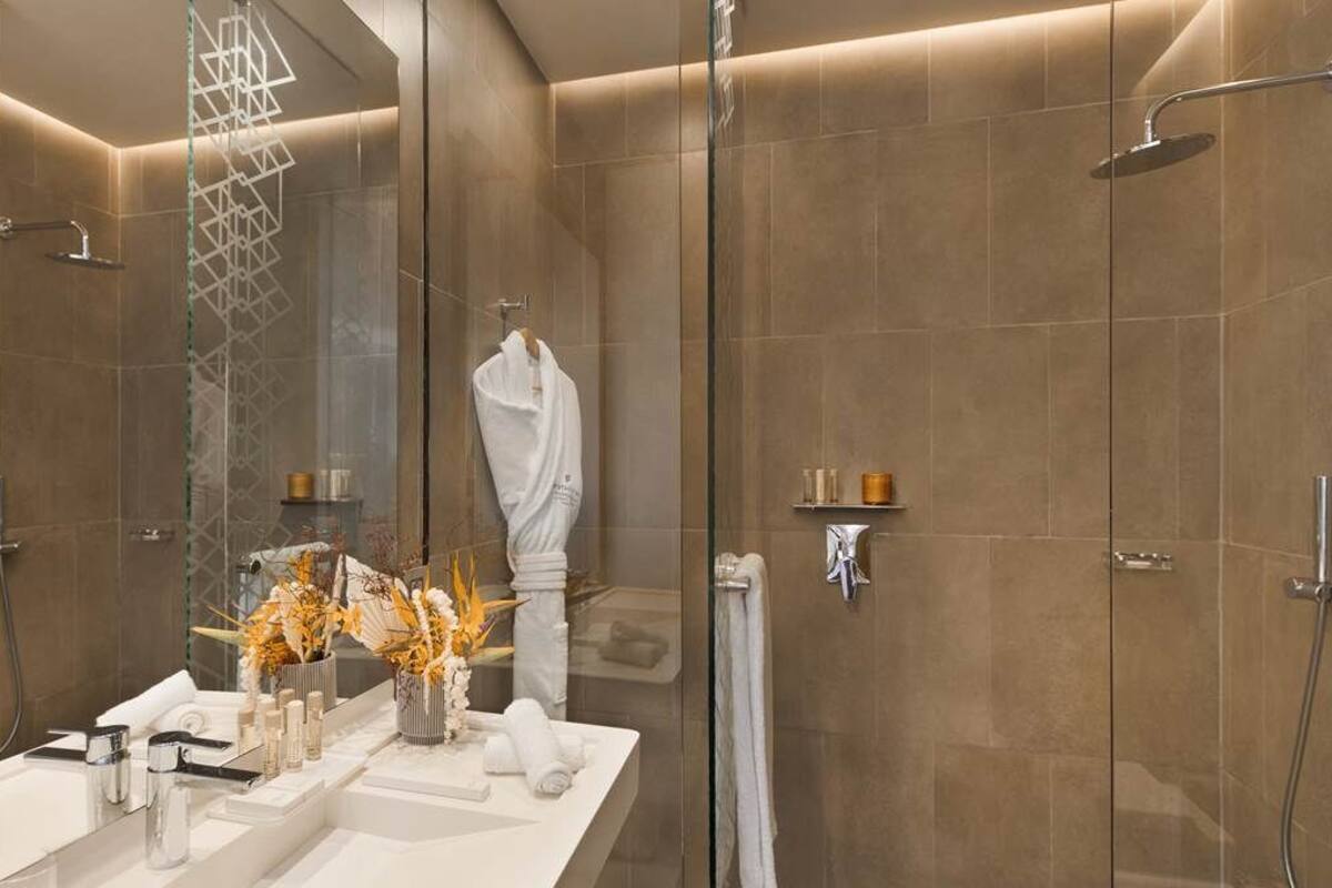 Een moderne badkamer met een douchecabine van glas, een wastafel met spiegel en een handdoekrek.