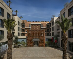 A modern hotel entrance with a geometric facade, palm trees, and a clear sky. - Pestana Cr7 Marrakech (Marrakech)