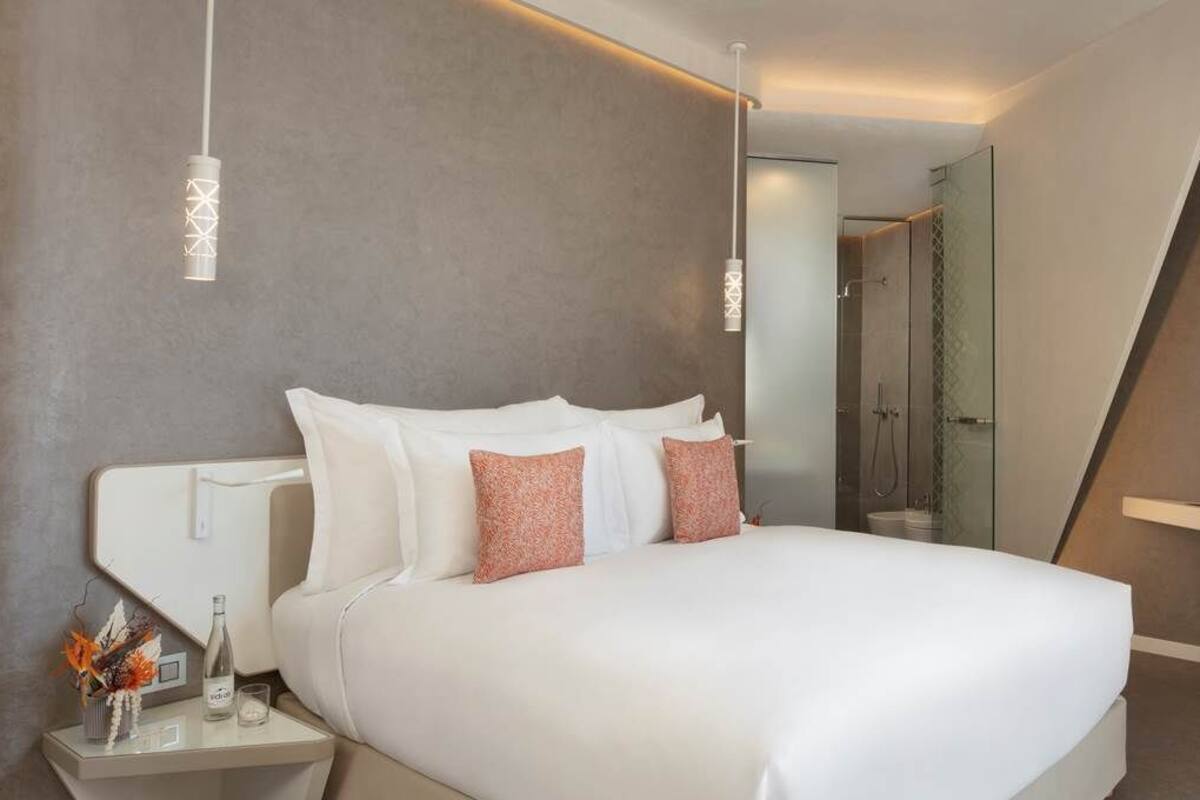 Een moderne hotelkamer met een groot bed, nachtkastjes, een spiegel en een douche.
