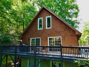A wooden cabin with a balcony, surrounded by trees.