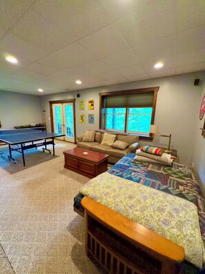 A room with a ping pong table, a sofa, a bed, and a window with a view. - ^ Blowing Rock ^ Renovated ^ Sleeps 10 ^ Game Room ^ App Ski Mnt ^ Tweetsie ^ (Blowing Rock)