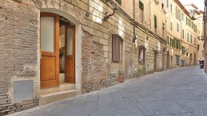 A narrow cobblestone street with historic stone buildings, wooden doors, and shutters. - Independent apartment near Piazza del Campo (Siena)