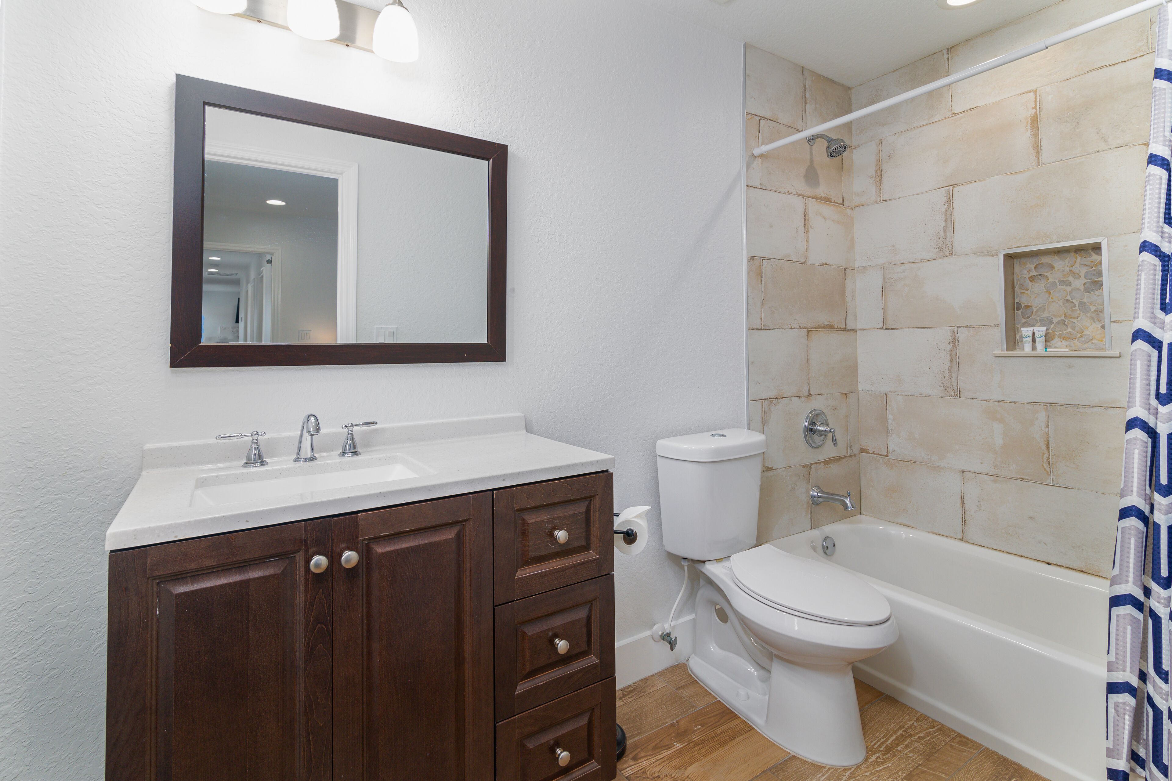 A bathroom with a white sink, dark wooden vanity, a white toilet, and a bathtub.
