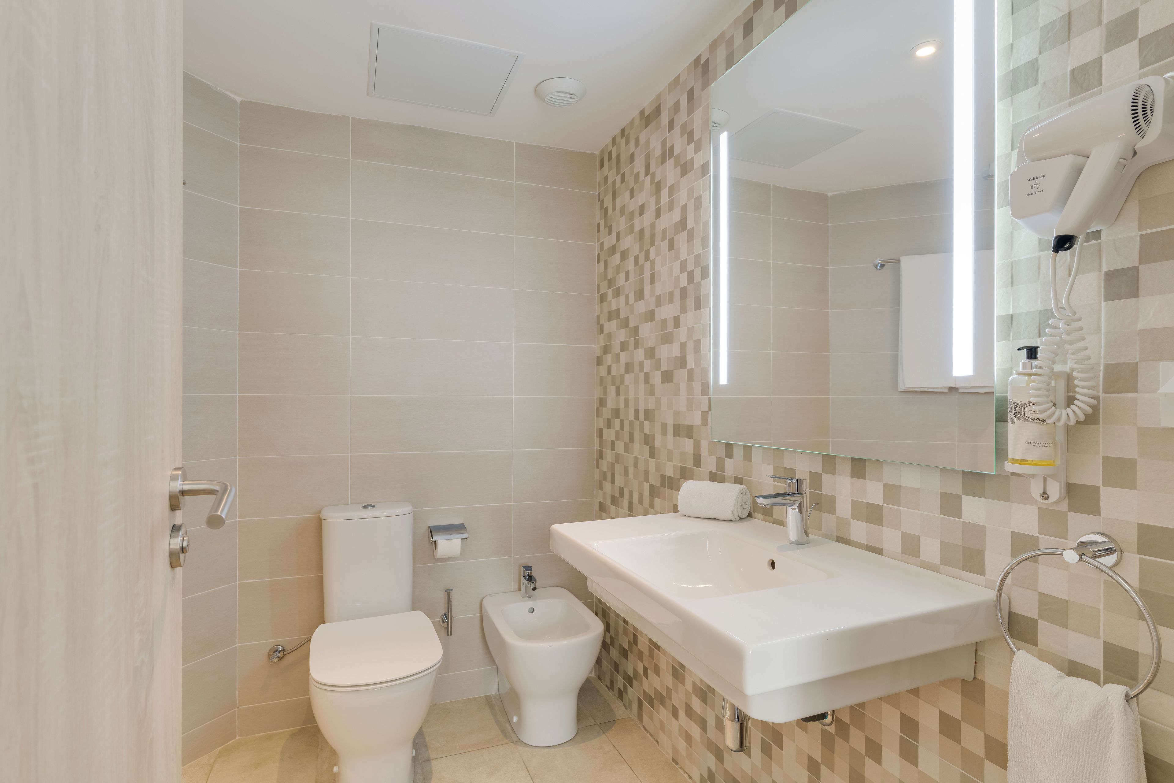 A modern bathroom with a toilet, bidet, and a sink with a towel rack.