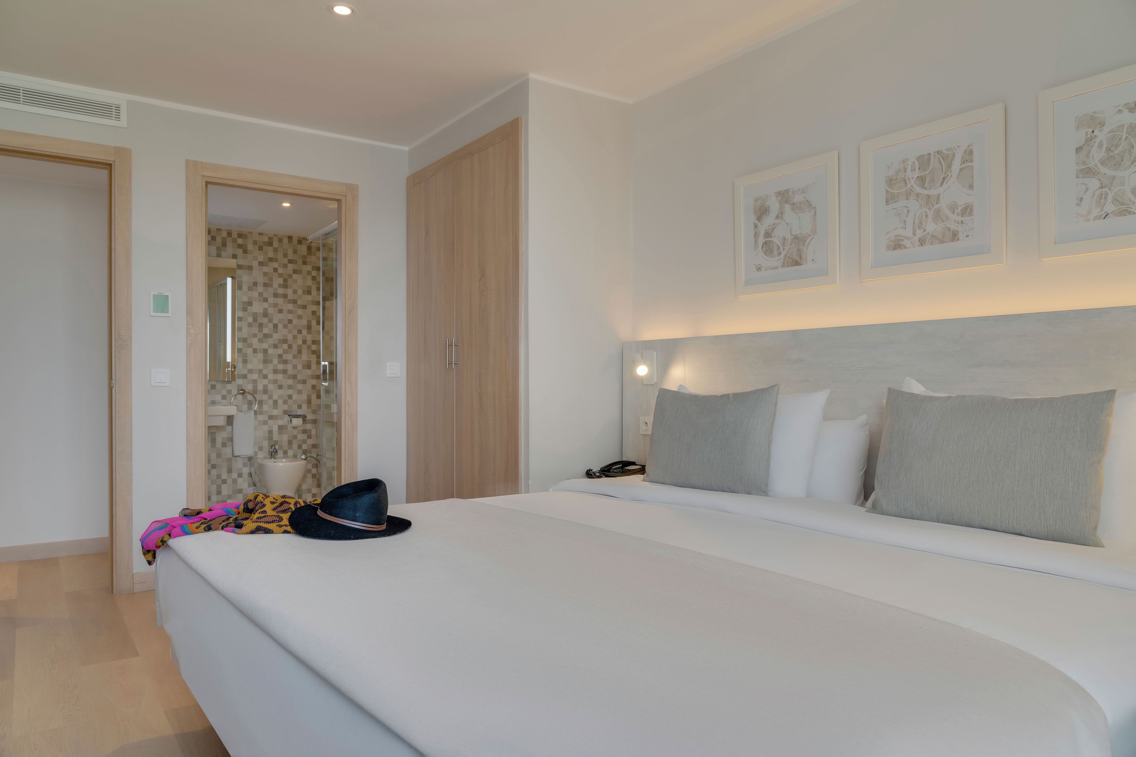 Une chambre d’hôtel avec un grand lit, une table de chevet avec un téléphone et une porte donnant sur une salle de bain.