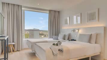 A modern hotel room with two beds, a desk, and a laptop.