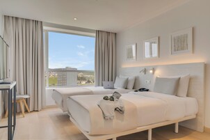 A modern hotel room with two beds, a desk, and a laptop.
