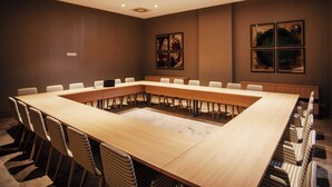 A conference room with a long table and chairs, recessed ceiling lights, and framed artwork on the walls. - Pestana Tanger - City Center Hotel Suites & Apartments (Tangier)