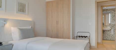Una habitación de hotel con cama, mesita de noche, lámpara y armario.