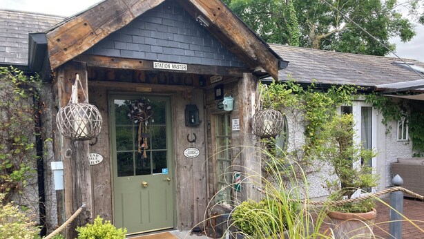 A rustic building with a green door, wooden exterior, and a sign reading "Station Master".