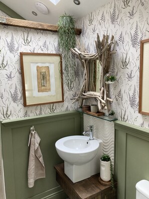 A bathroom with a sink, a framed picture, a hanging plant, and a decorative wooden structure. - Ballybur lodge Mews1. (Kilkenny)