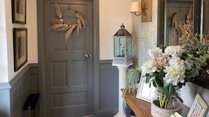 A hallway with a grey door, a lantern, and a vase of flowers.