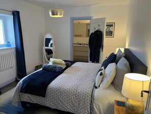 Un dormitorio ordenado con cama, lámpara de noche y espejo.