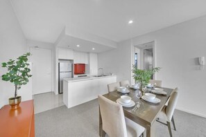 A modern kitchen with white cabinets, a red appliance, and a dining area with a wooden table set for four.