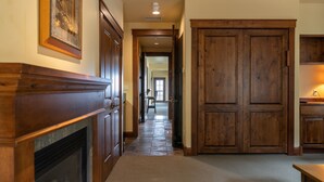 A hallway with a fireplace, wooden doors, and a carpeted floor. - Grand View 3330: Top Floor Condo w/ Spectacular Teton Views- Air Conditioned! (Jackson)
