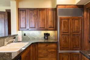 Una cocina con gabinetes de madera, un lavamanos empotrado y una cafetera.