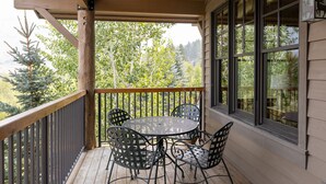 A wooden deck with a table and chairs, large windows, and a view of trees. - Grand View 3330: Top Floor Condo w/ Spectacular Teton Views- Air Conditioned! (Jackson)
