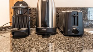 A kitchen with a coffee maker, a kettle, and a toaster on a granite countertop. - Spacious Duplex Close to all Cultural Sites (Brussel)