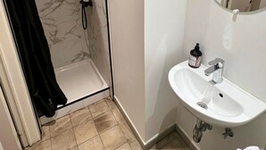 Ein Badezimmer mit Dusche, Waschbecken und Spiegel.
