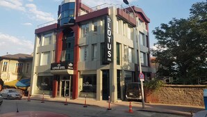 Un edificio moderno con un llamativo letrero de 'LOTUS OTEL', fachada de vidrio y una pared de acento roja.