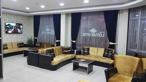 Un área de descanso moderna con sofás, sillones, un televisor de pantalla plana y cortinas con un logotipo.