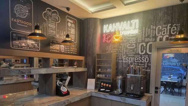 Un interior de restaurante con mostrador, paneles de menú y una máquina de café.