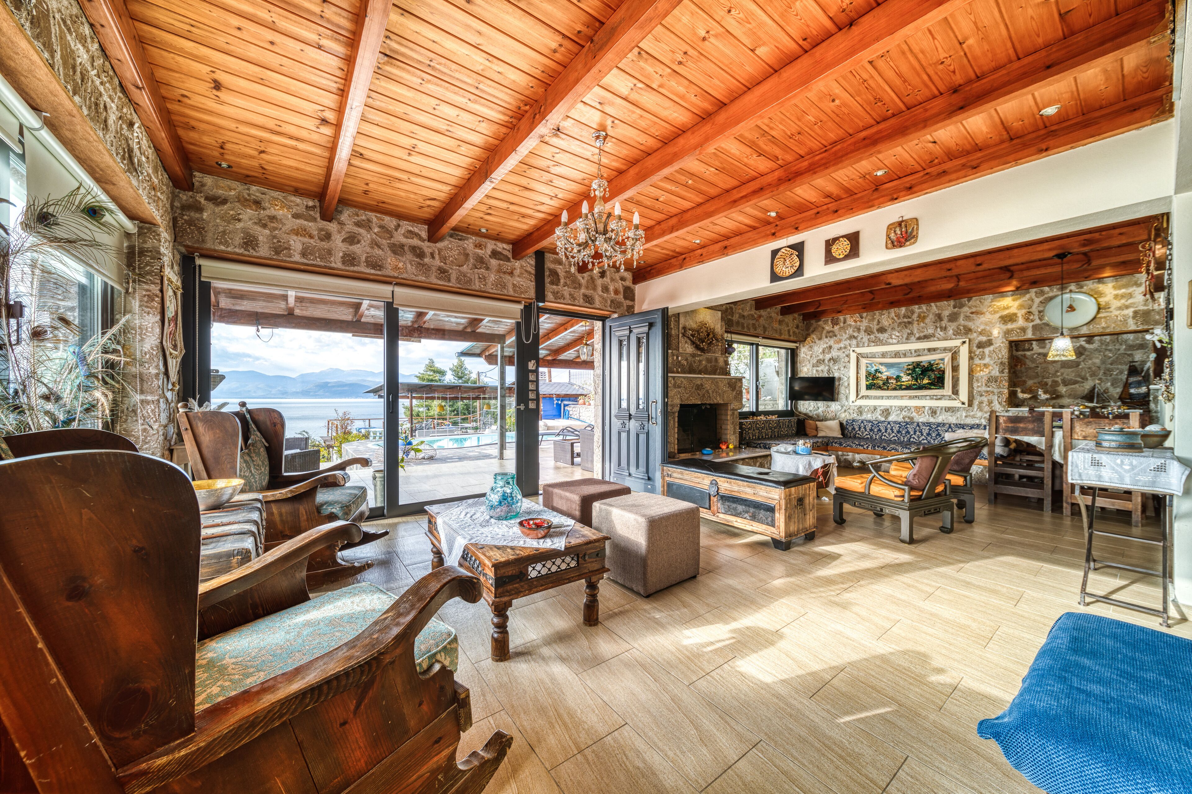 A spacious living area with wooden furniture, a stone wall, and a view of the mountains.