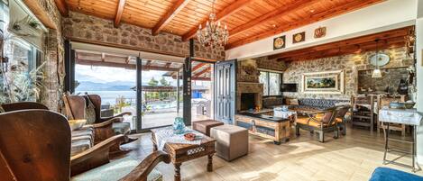 A spacious living area with wooden furniture, a stone wall, and a view of the mountains.