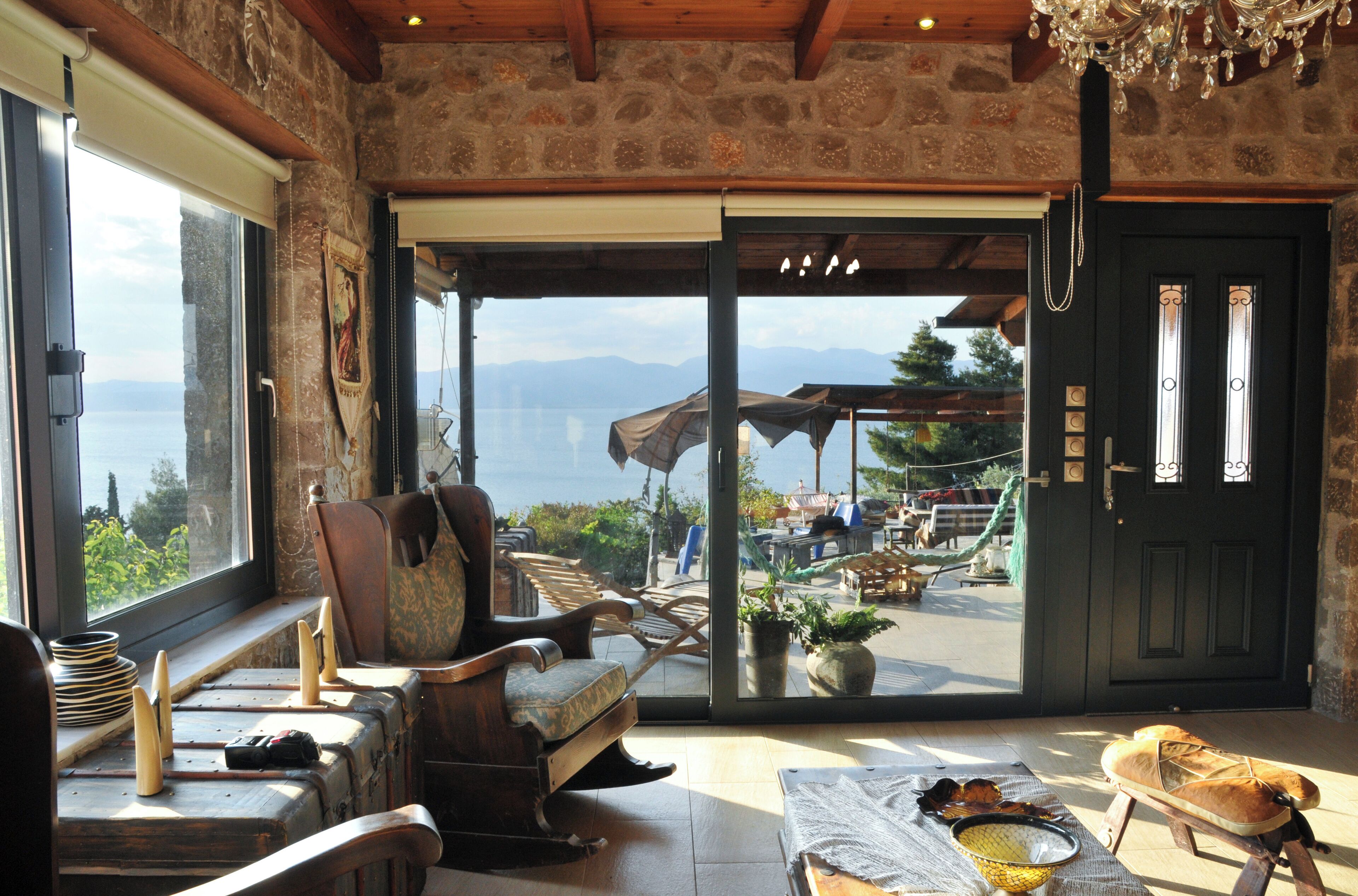 A room with a view of the sea, a wooden ceiling, and a door leading outside.