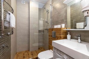 Ein modernes Badezimmer mit einer Duschkabine aus Glas, einem Holzboden und einem Waschbecken sowie einer Toilette.