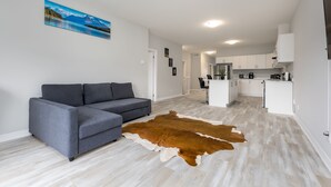Una sala de estar moderna con un sofá gris, un tapiz de cuero de vaca y un cuadro de un paisaje montañoso.