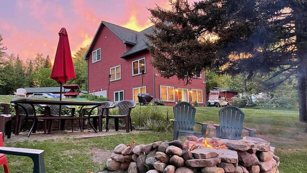A red house with a fire pit and outdoor seating. - Adirondack Hideout, lakefront location and sandy shoreline (Lyon Mountain)