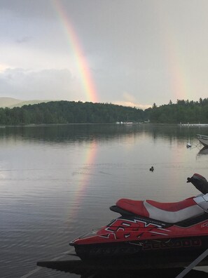 A jet ski on a calm lake with a rainbow in the background. - Adirondack Hideout, lakefront location and sandy shoreline (Lyon Mountain)