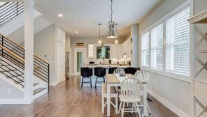 Una cocina amplia con una isla central, muebles blancos y un comedor con mesa y sillas.
