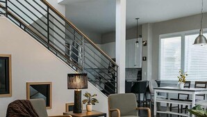 Una sala de estar moderna con una escalera, muebles de madera y una alfombra grande.