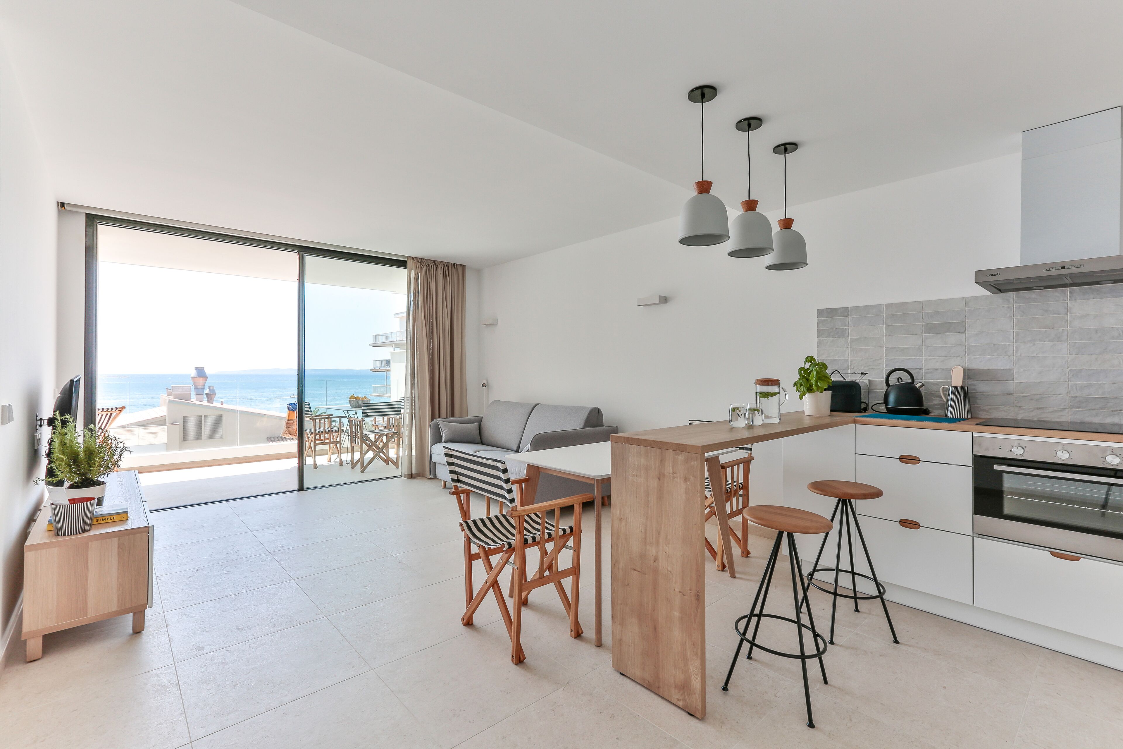 A modern kitchen with a large island, bar stools, and a view to the outside.