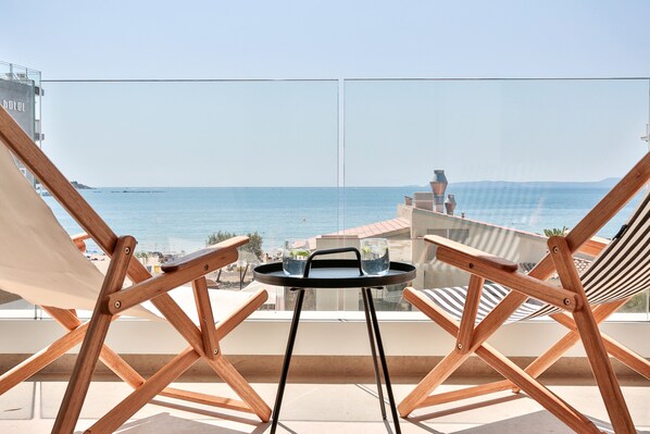 A balcony with two wooden chairs and a small table, overlooking a clear blue sea and distant land. - ECO-APARTMENTS LA MARINEDA & HOTEL THALASSA SPORT & SPA (Roses)