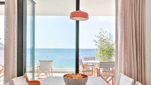A dining area with a view of the sea, a table with a bowl of fruit, and a hanging red light fixture. - ECO-APARTMENTS LA MARINEDA & HOTEL THALASSA SPORT & SPA (Roses)