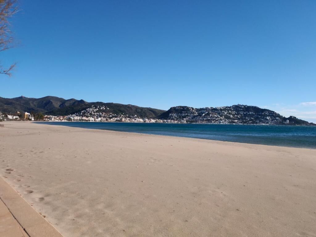 A beach with a clear view of the coastline and mountains in the background.