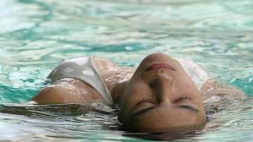 Une personne allongée dans une piscine à l’eau claire.