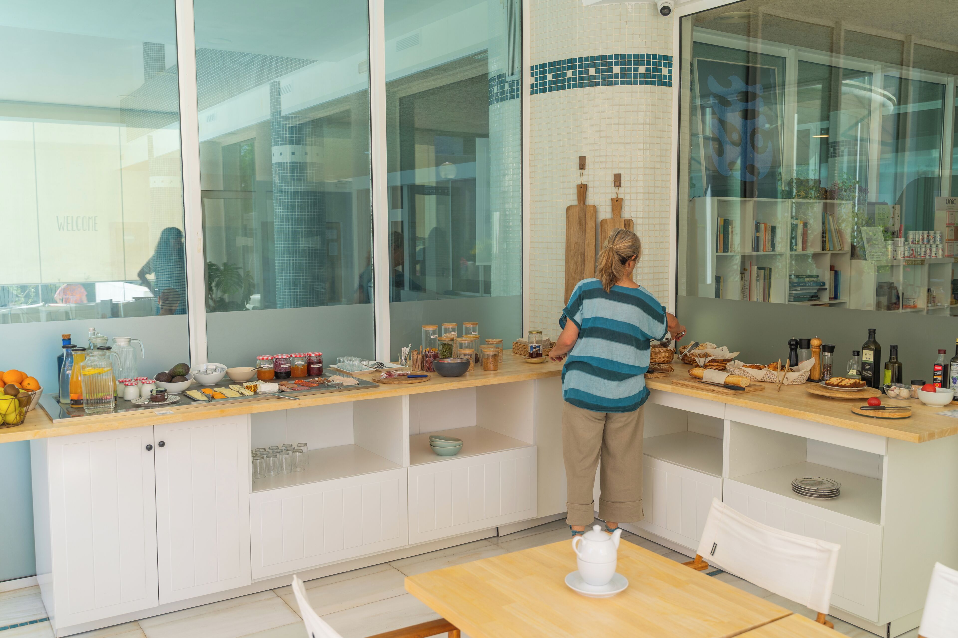Een moderne keuken met witte kasten, een houten aanrecht en een groot raam.