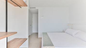 Een slaapkamer met een bed, een houten schapunit en een deur die naar een andere kamer leidt.
