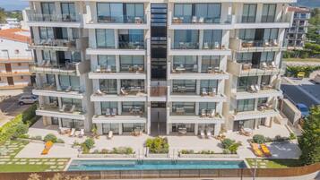 Un hotel de varios pisos con balcones, piscina y zona de estacionamiento.