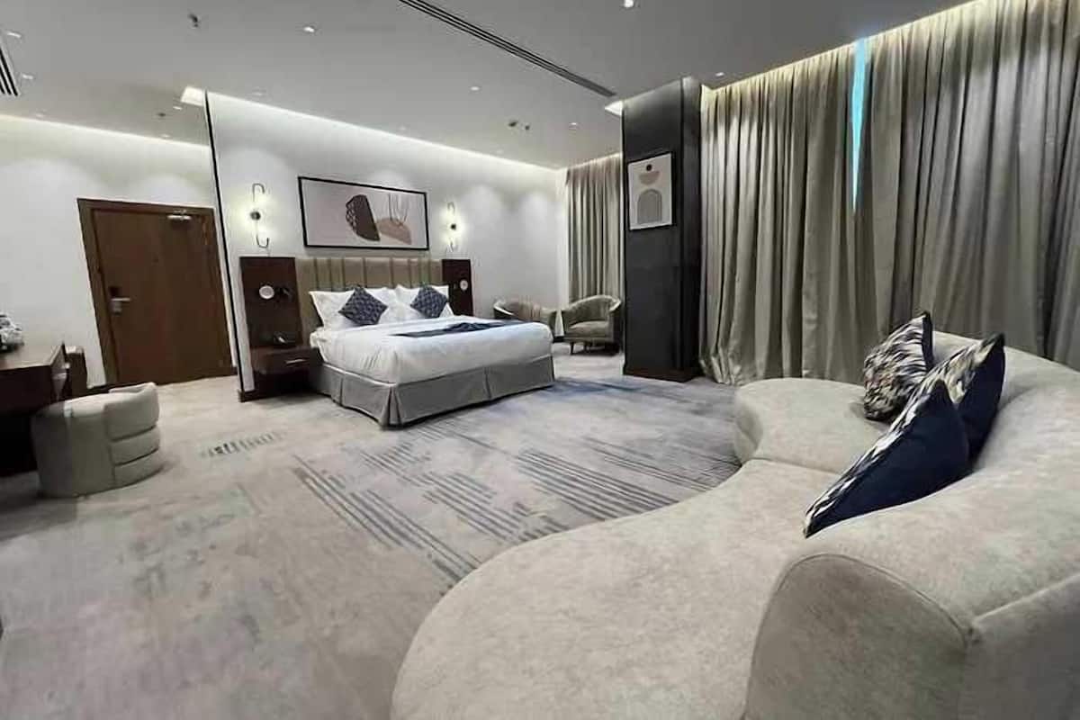 Una habitación de hotel moderna con una cama grande, un sofá, un escritorio y una silla.